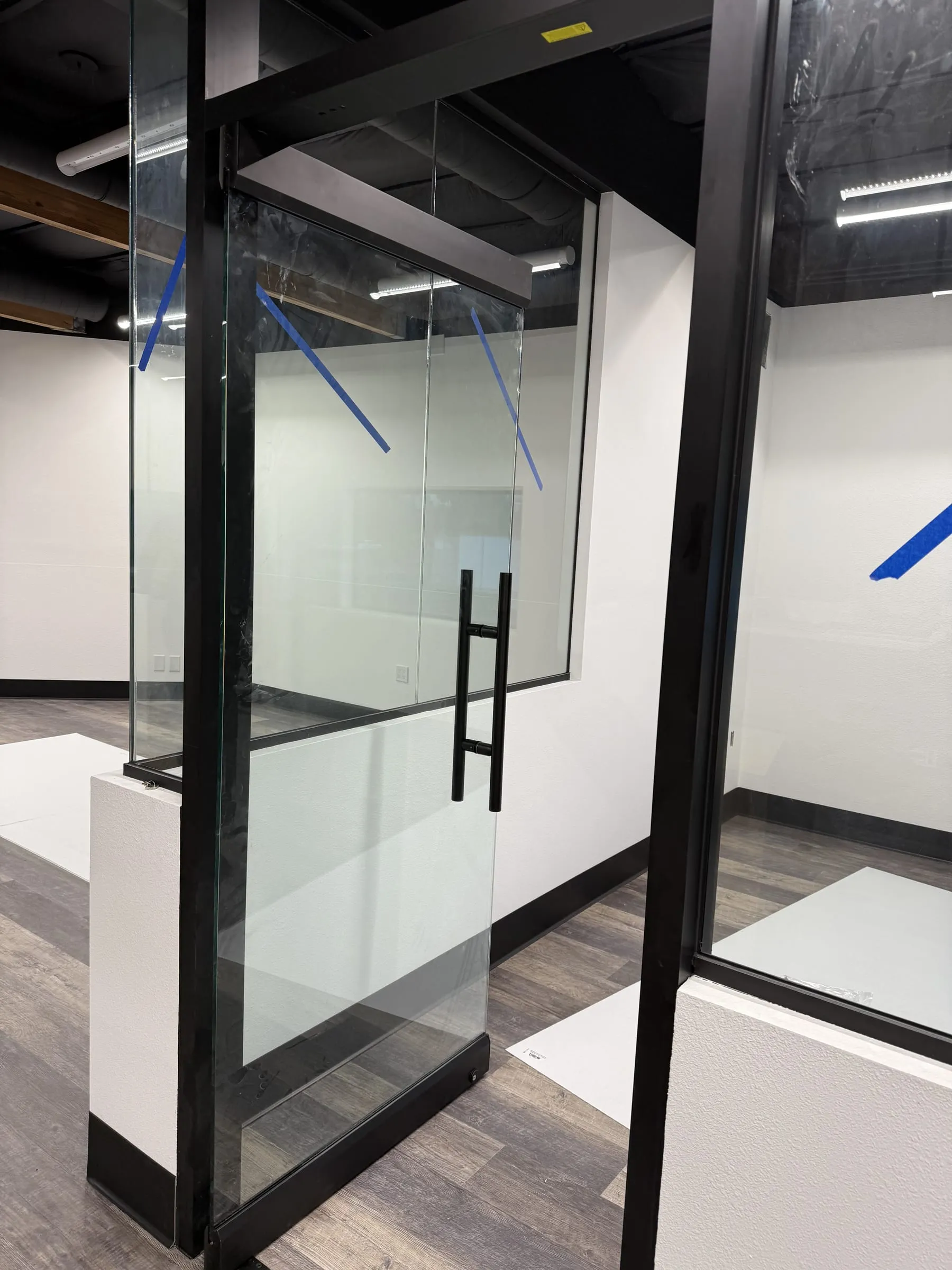 Glass door with a long pull between black-framed glass partitions
