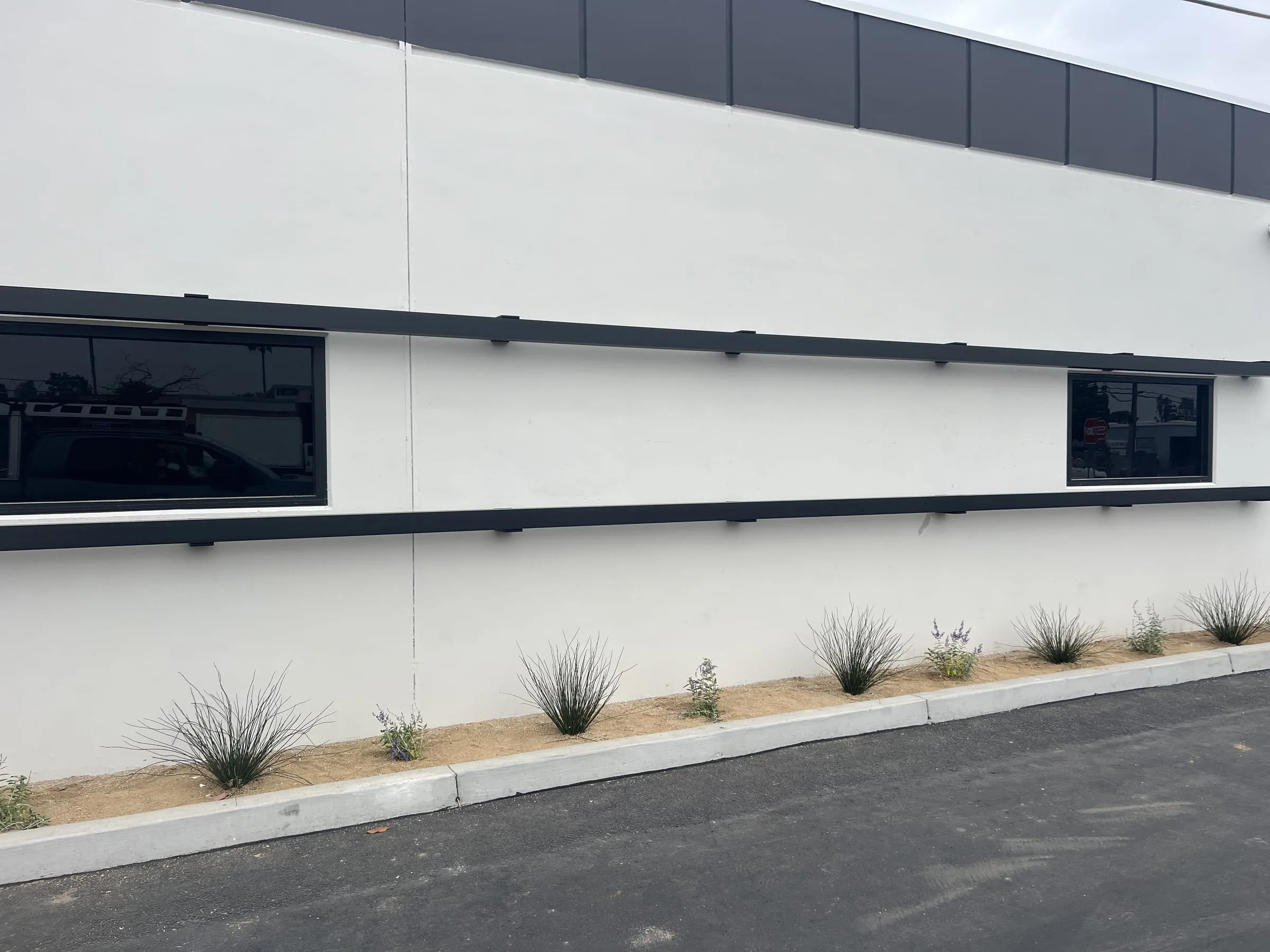 White commercial facade with black-framed windows and black horizontal bands