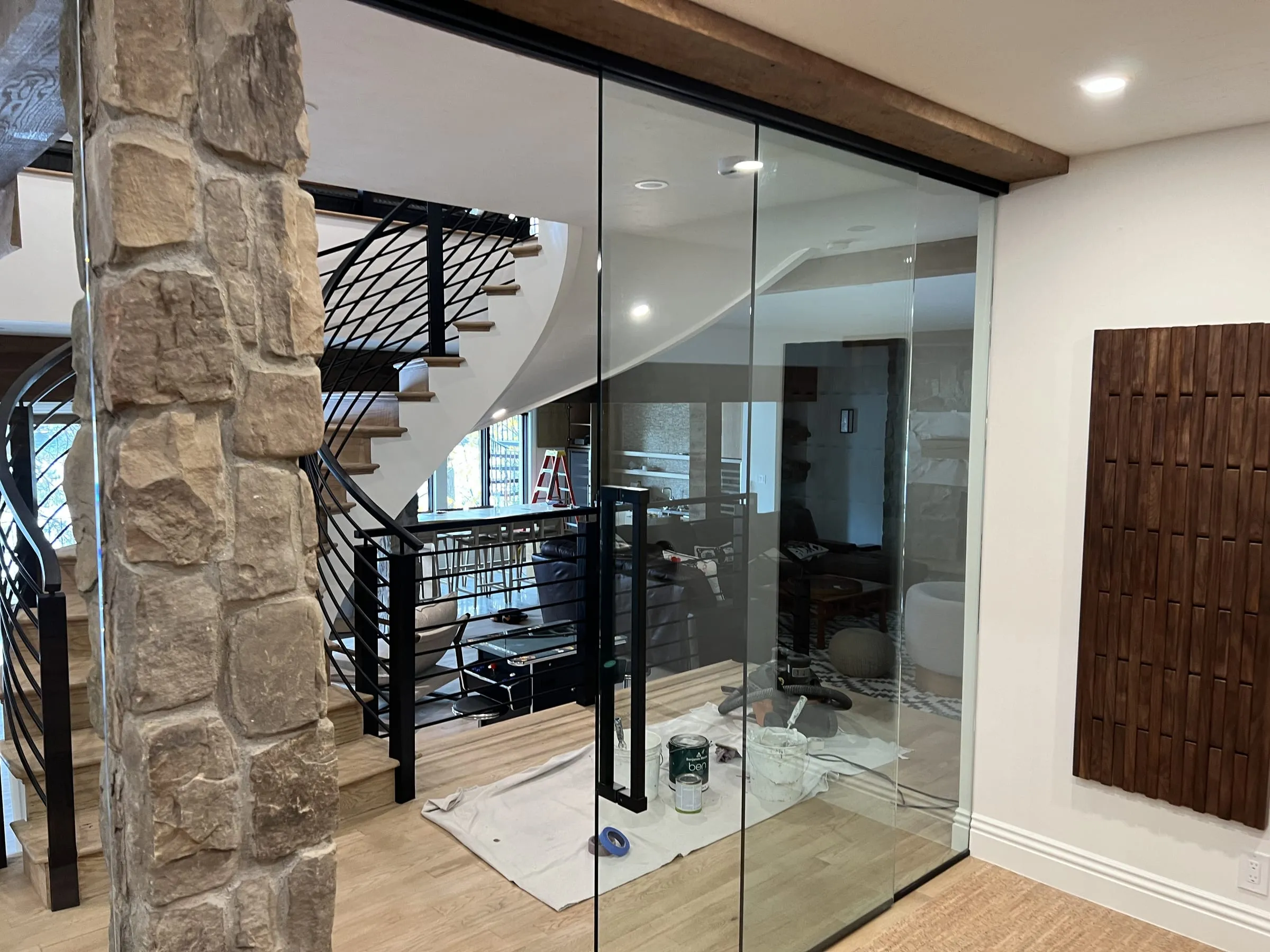 Frameless glass partition with a sliding glass door beside a stone column
