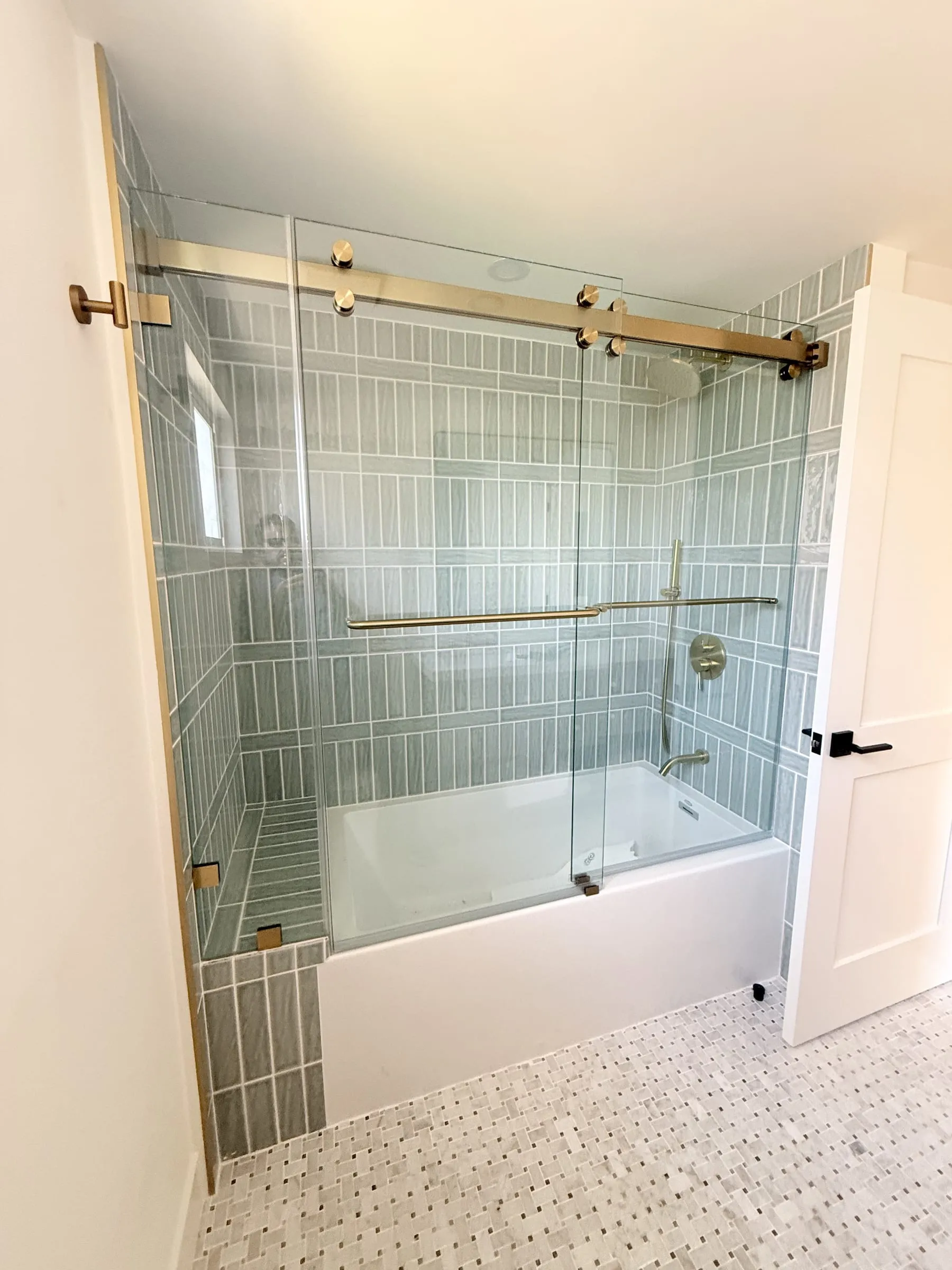 Bathtub with frameless sliding glass doors on a brass track