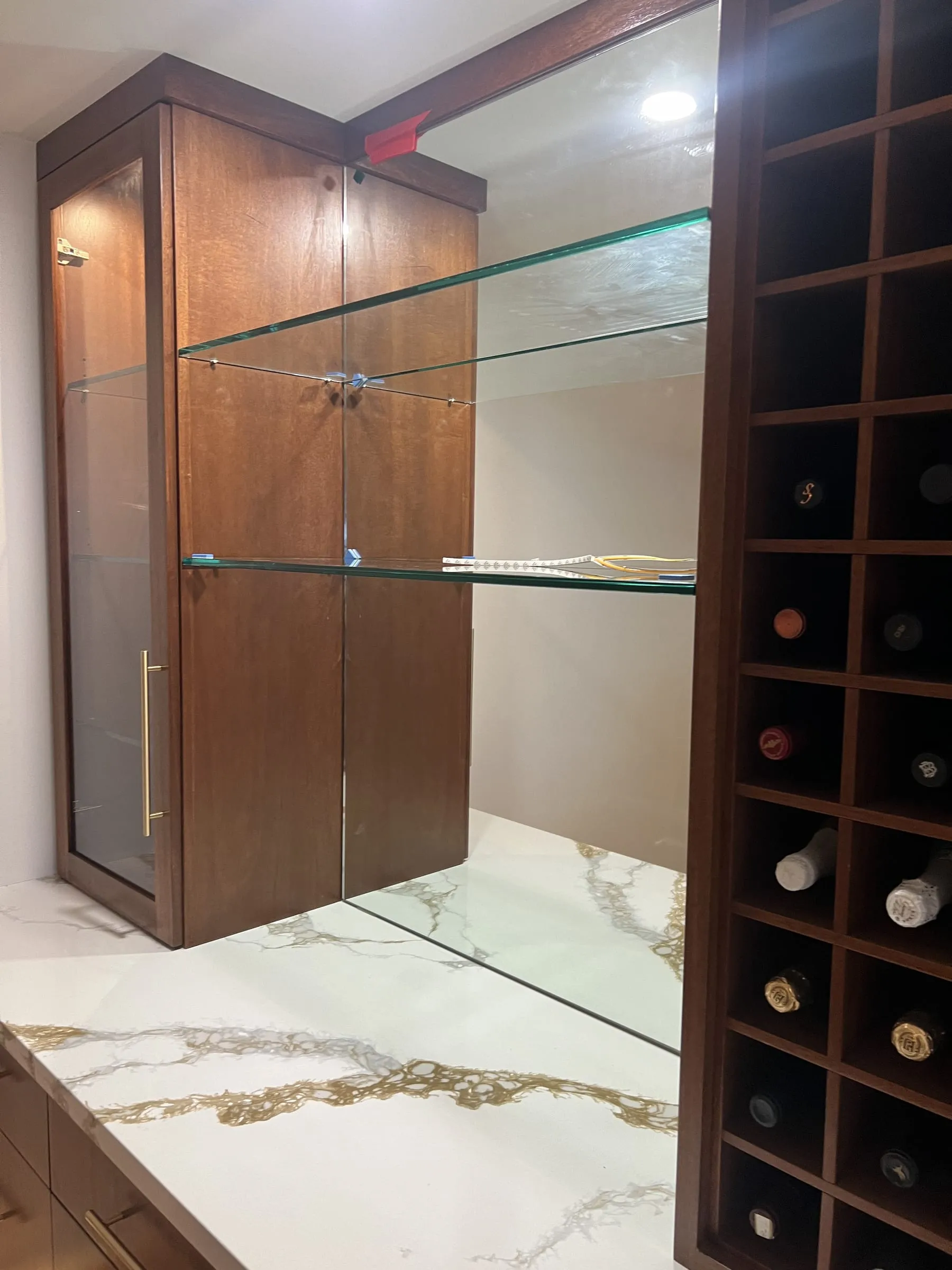 Glass shelves and glass doors in a bar cabinet with a mirrored back