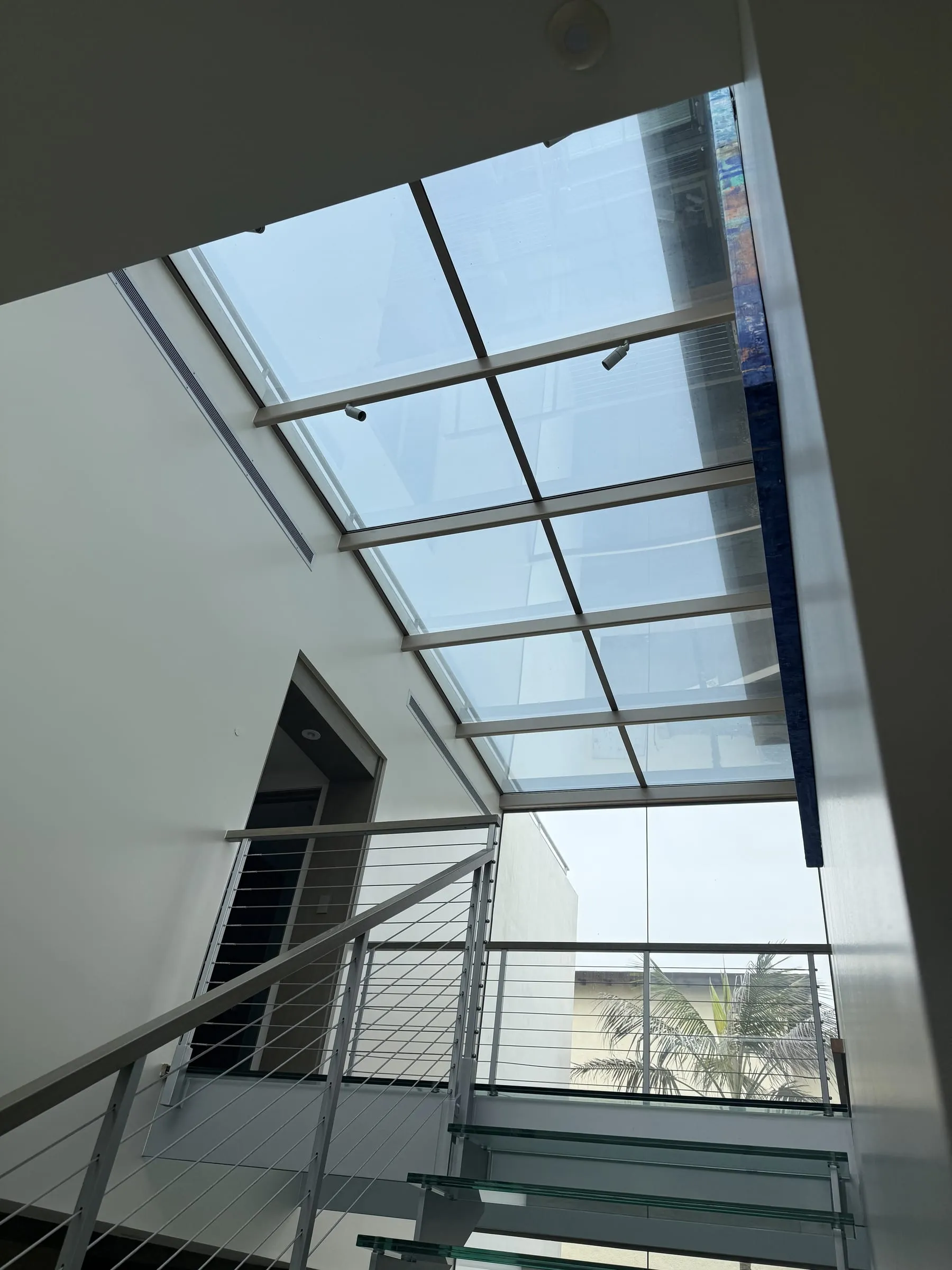 Glass skylight roof above a stairwell with cable railings