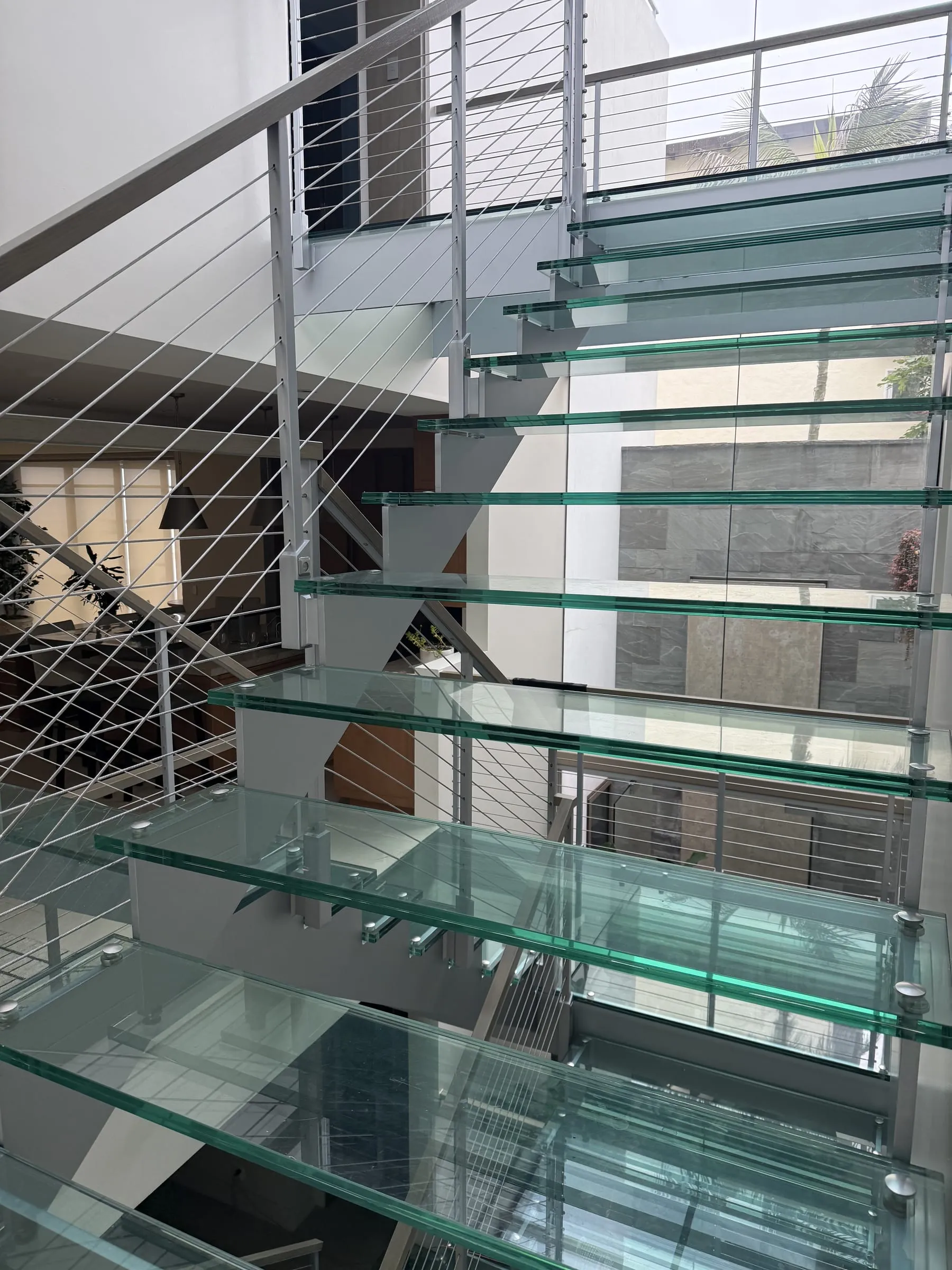 Glass stair treads seen from above beside a cable railing