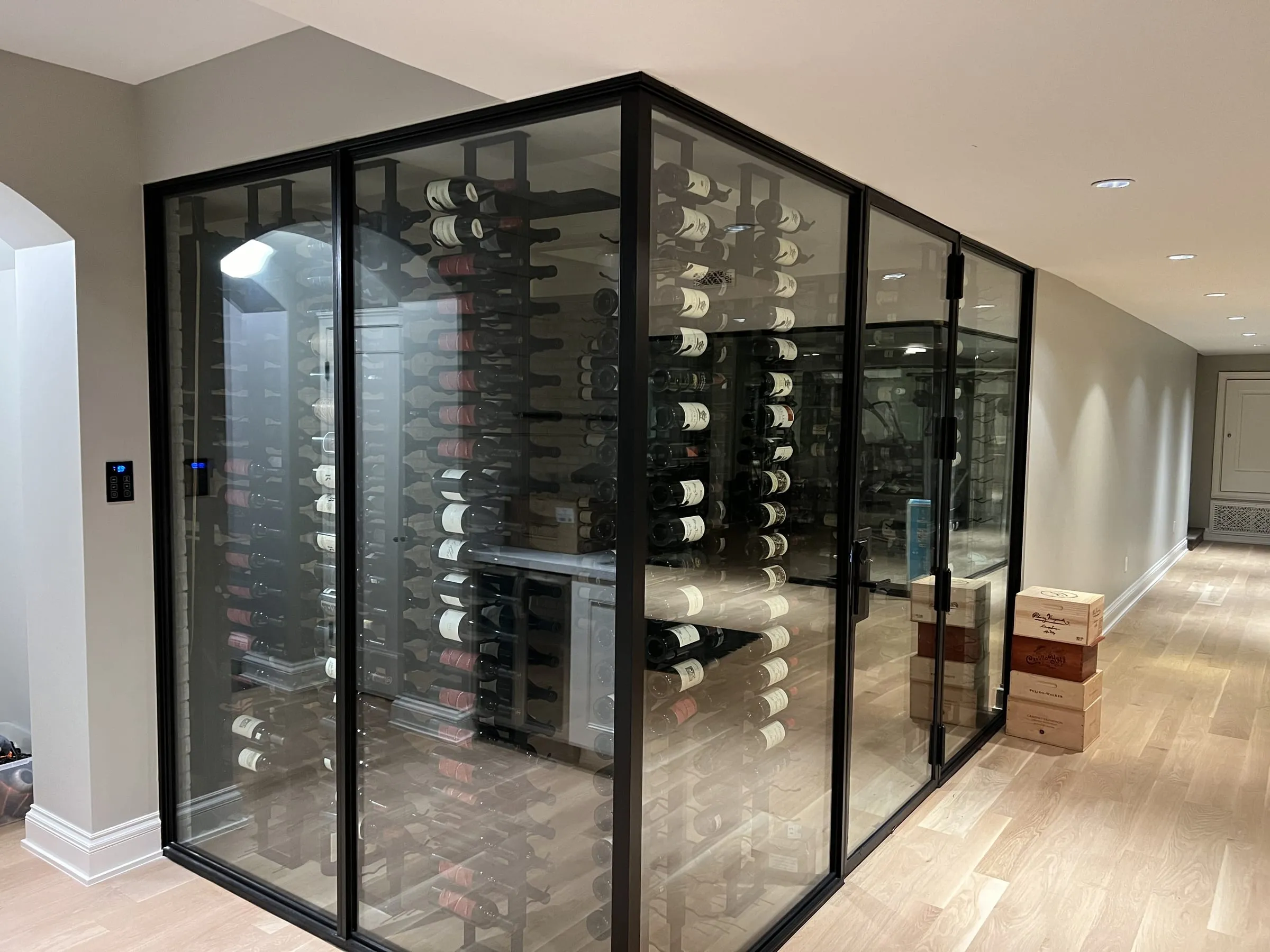 Black-framed glass wine cellar with a glass door and racks of wine bottles