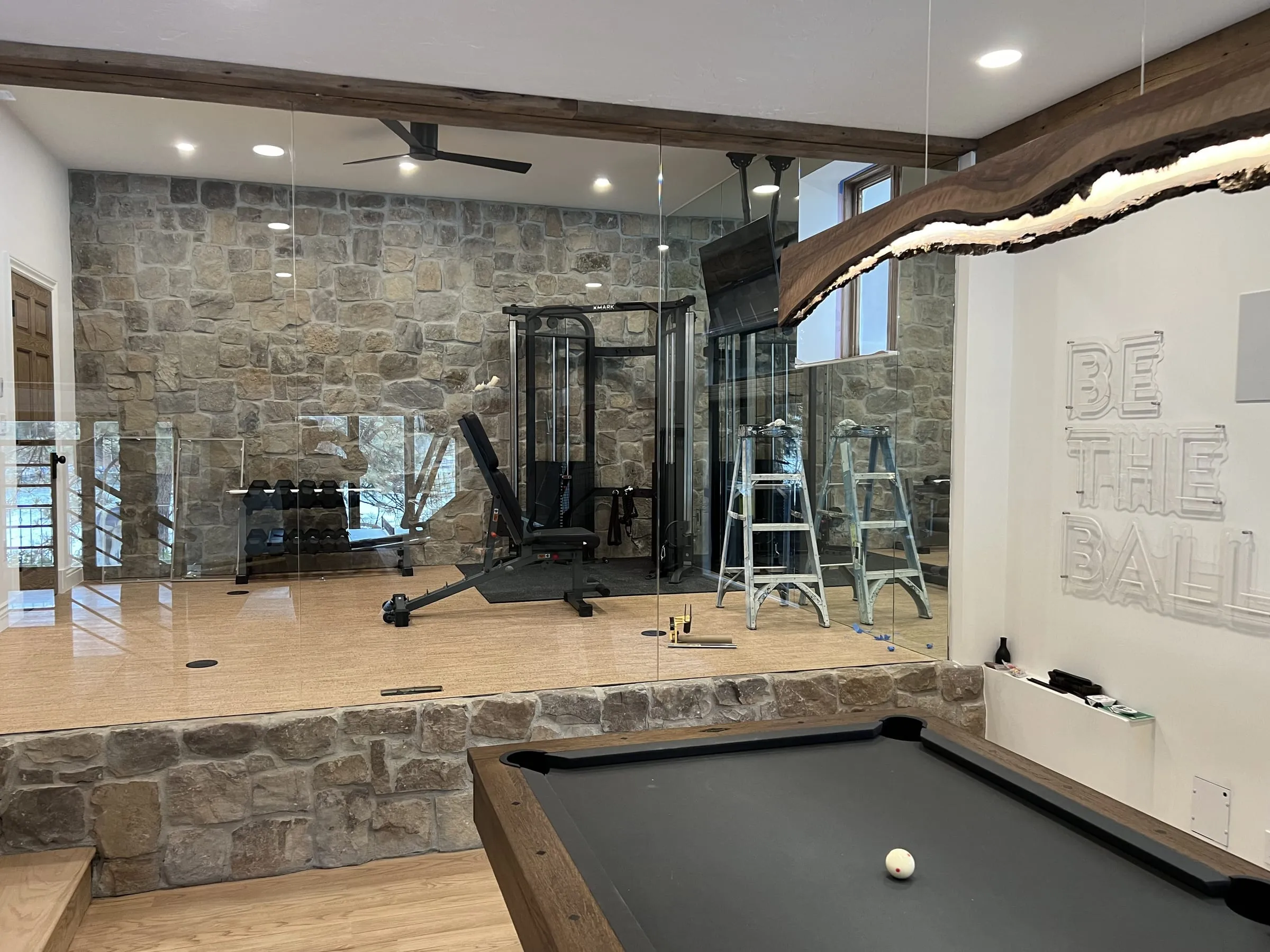 Raised home gym behind frameless glass on a stone knee wall