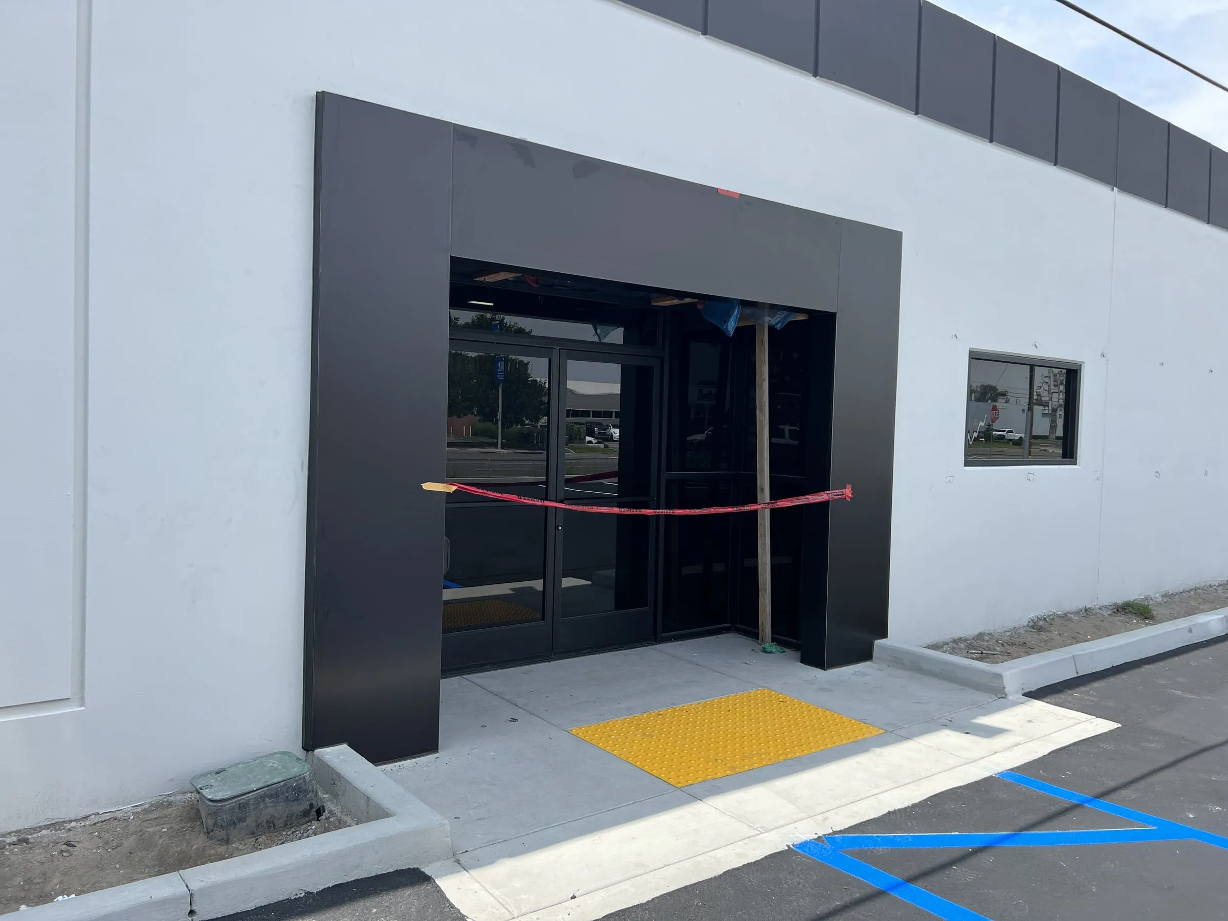 Commercial storefront entrance with black-framed glass doors, transom and sidelights inside a dark portal